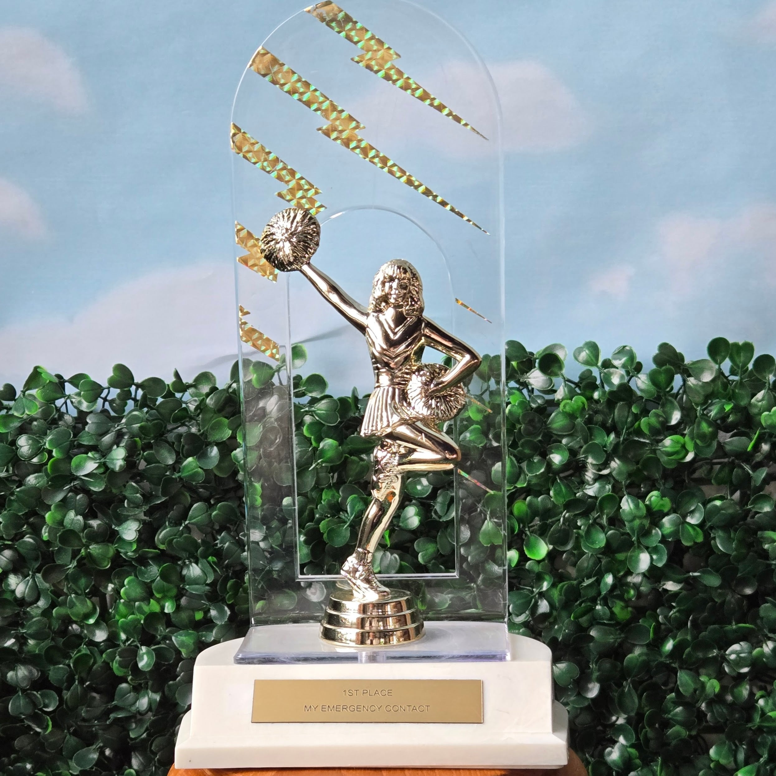 Trophy with a figure on a wooden base against a green hedge background