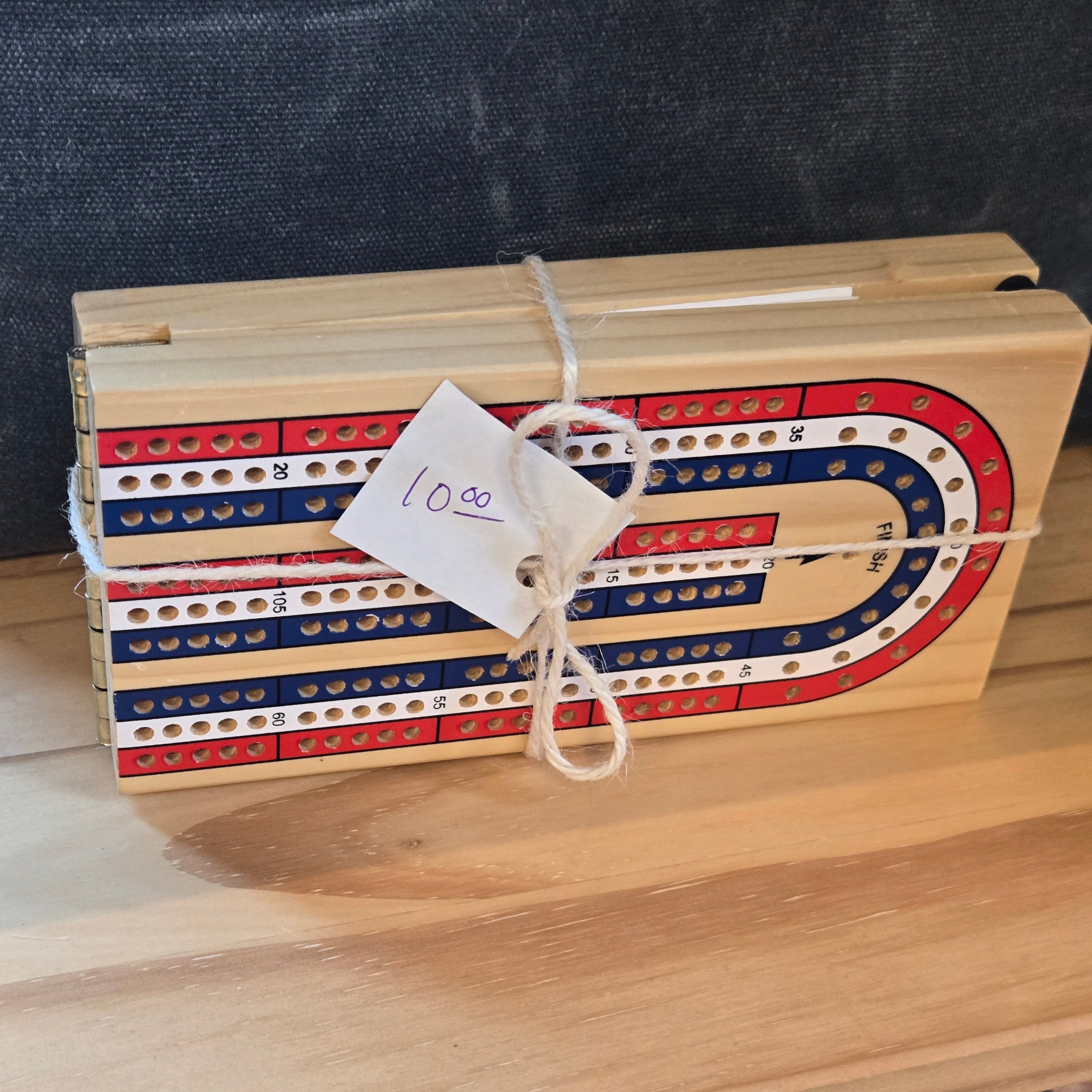 Wooden cribbage board with red, white, and blue stripes on a wooden surface.